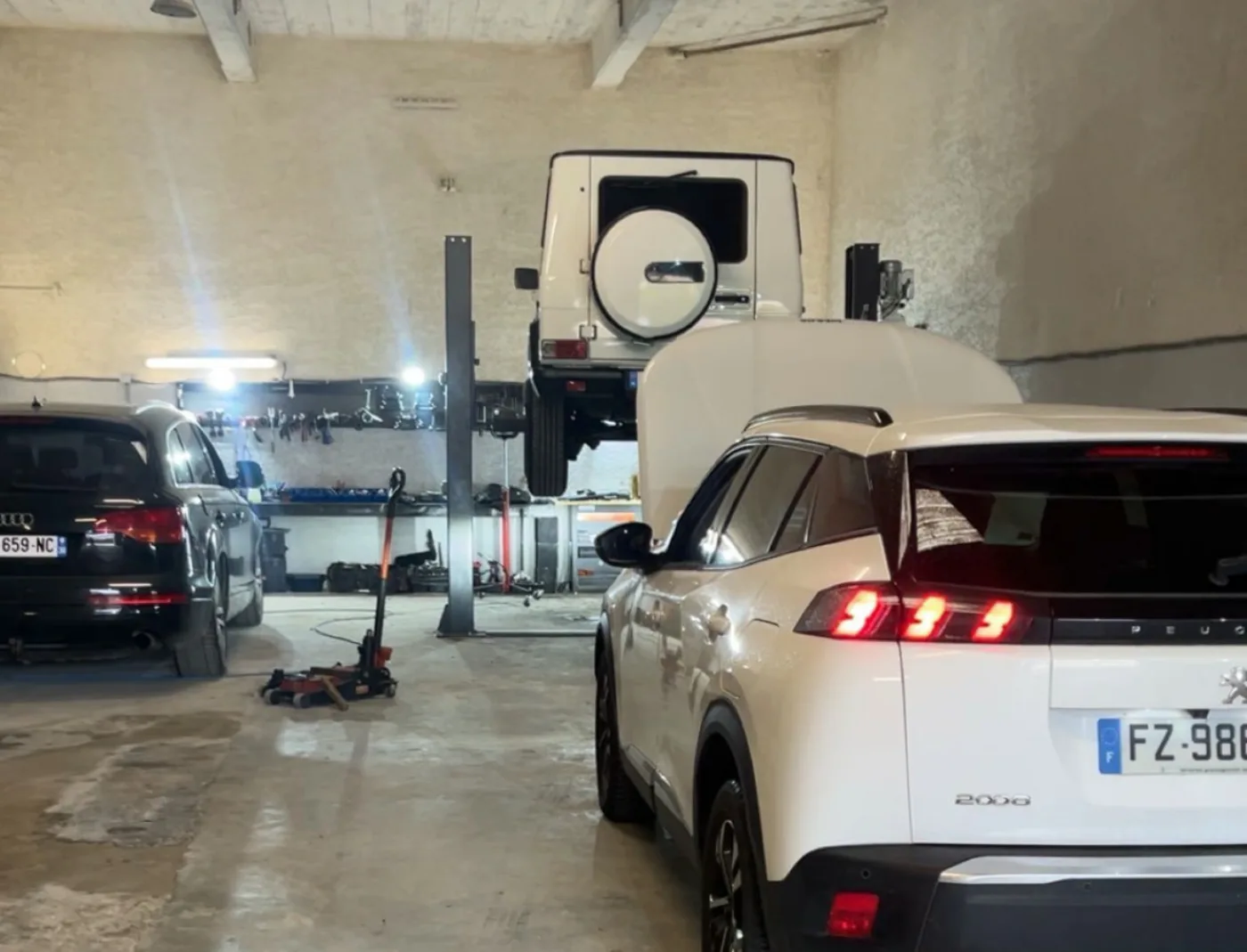 Véhicules sur pont élévateur dans l'atelier du garage ISLK