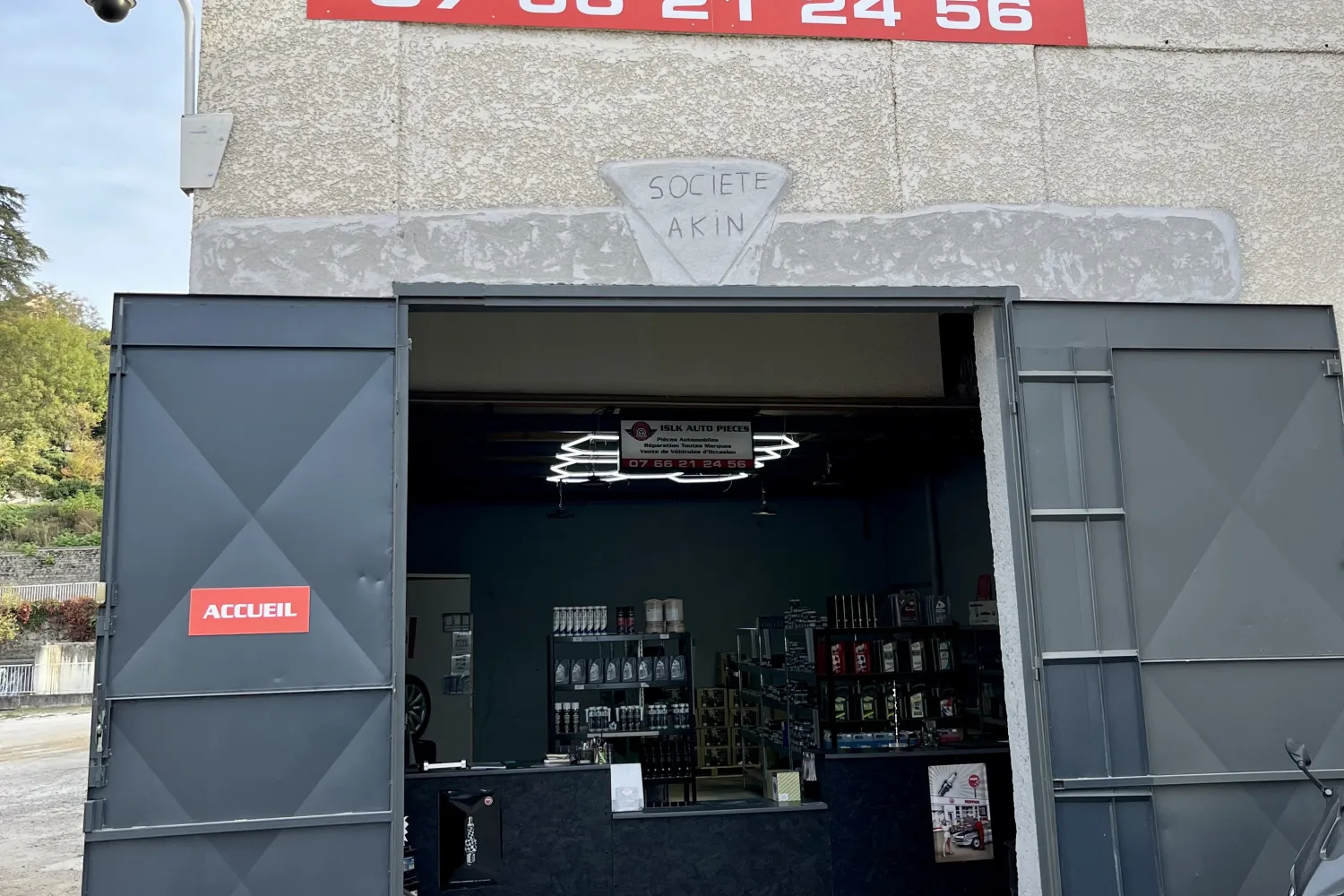 Façade et porte du garage ISLK Auto Pièces, zone industrielle des Forges à Pont-Évêque