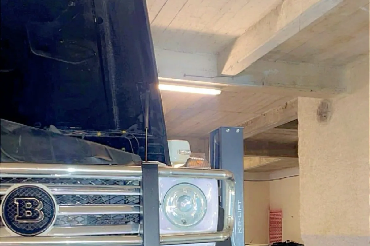 Véhicule levé sur le pont élévateur, capot ouvert, dans l'atelier ISLK