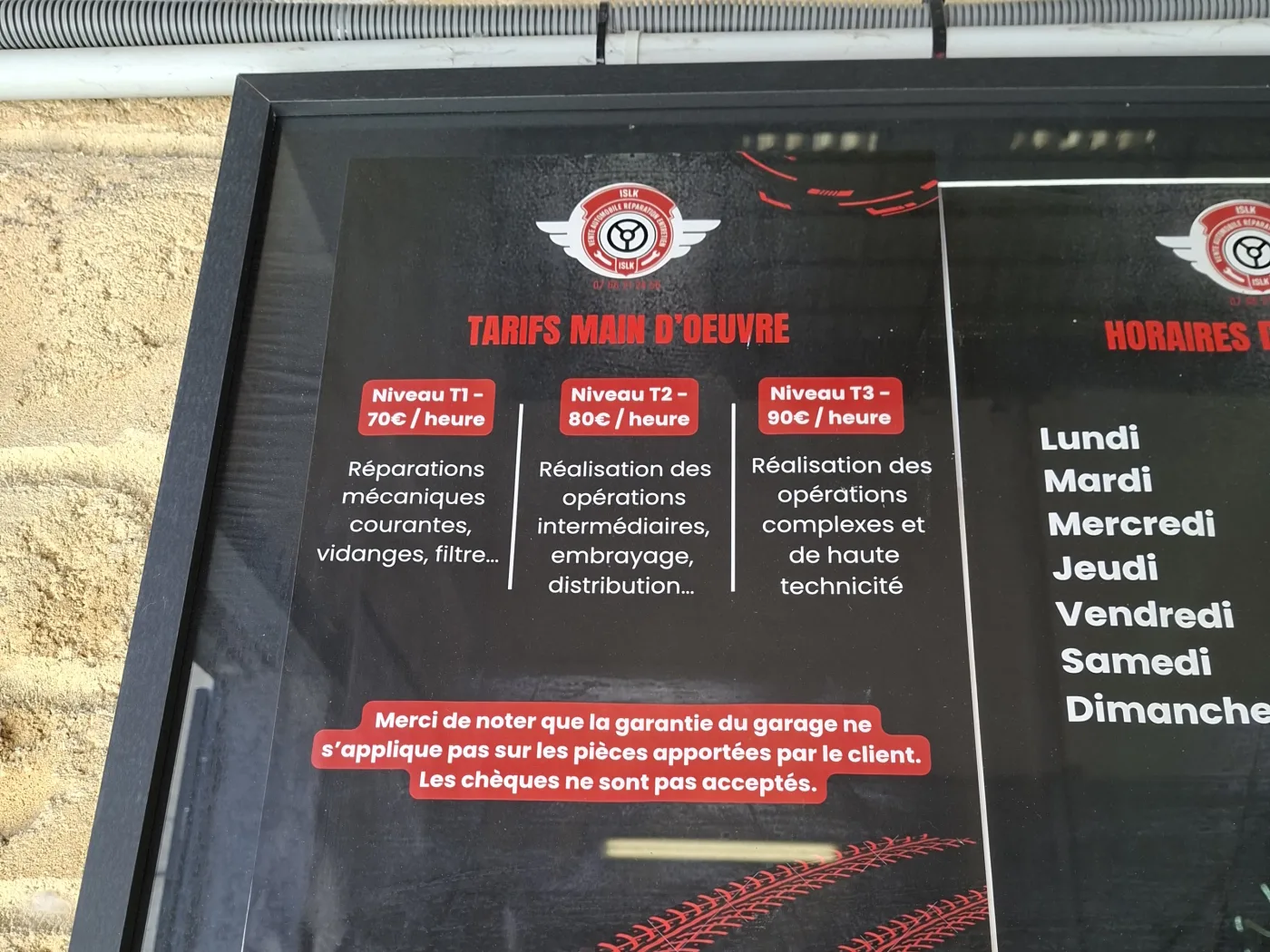 Panneau des tarifs de main-d'œuvre affiché à l'entrée du garage ISLK