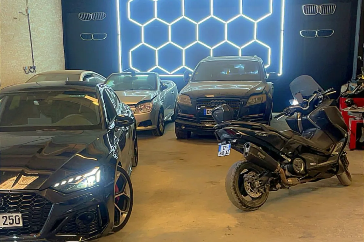 Voitures et motos stationnées dans le box du garage ISLK sous l'éclairage hexagonal